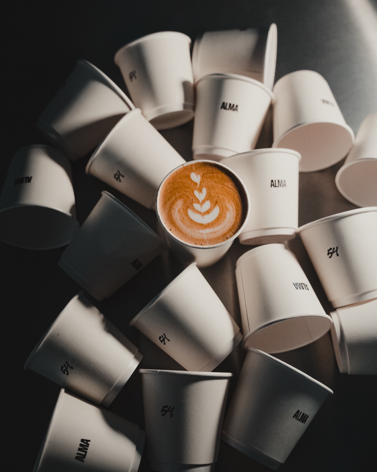 Alma54 branded coffee cups with latte art