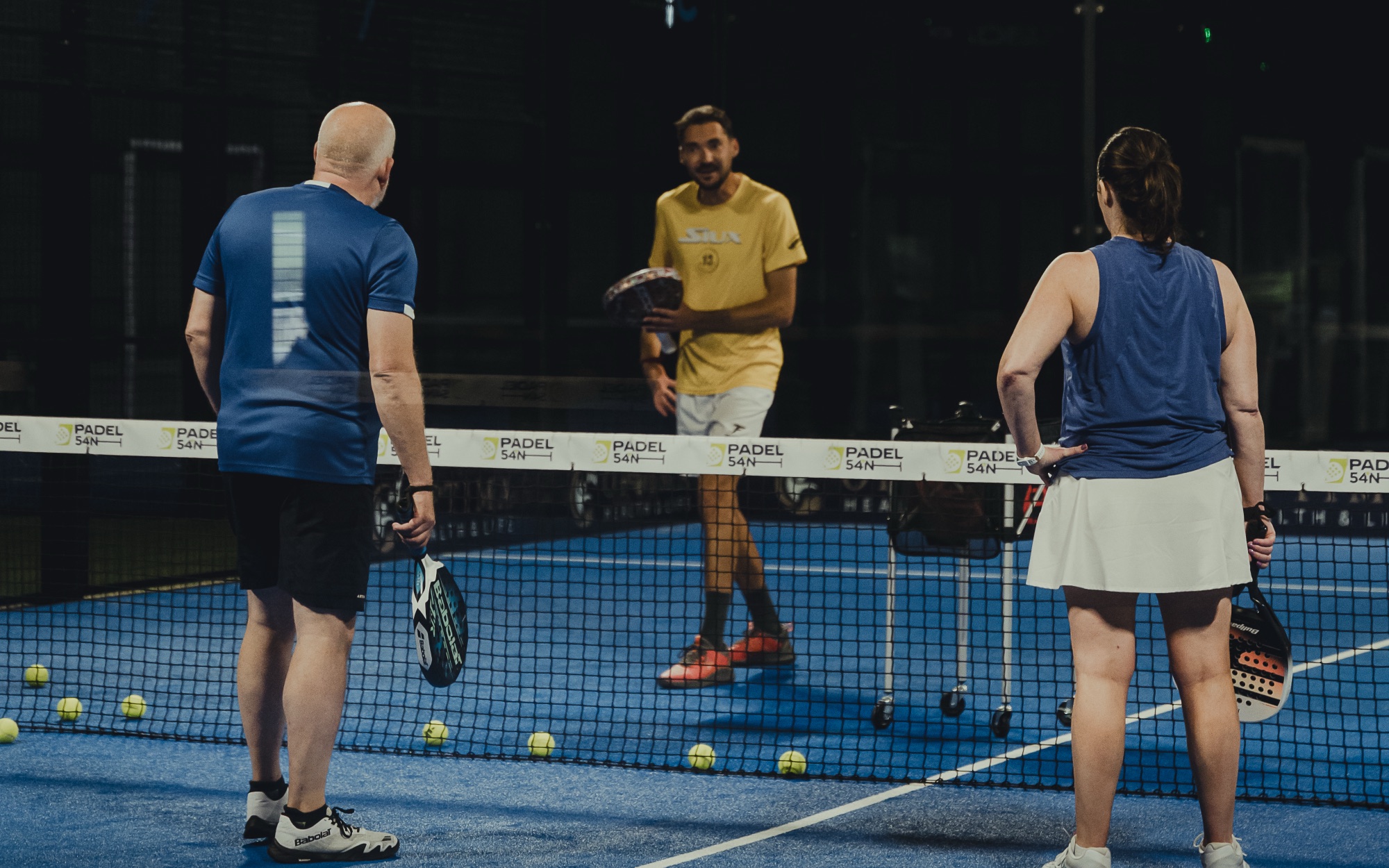 A coach feeding balls during a session at Padel54