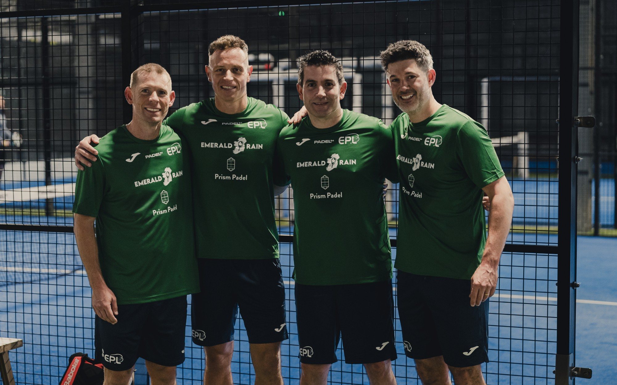 Four Emerald Rain players in green Padel54 shirts smiling on court