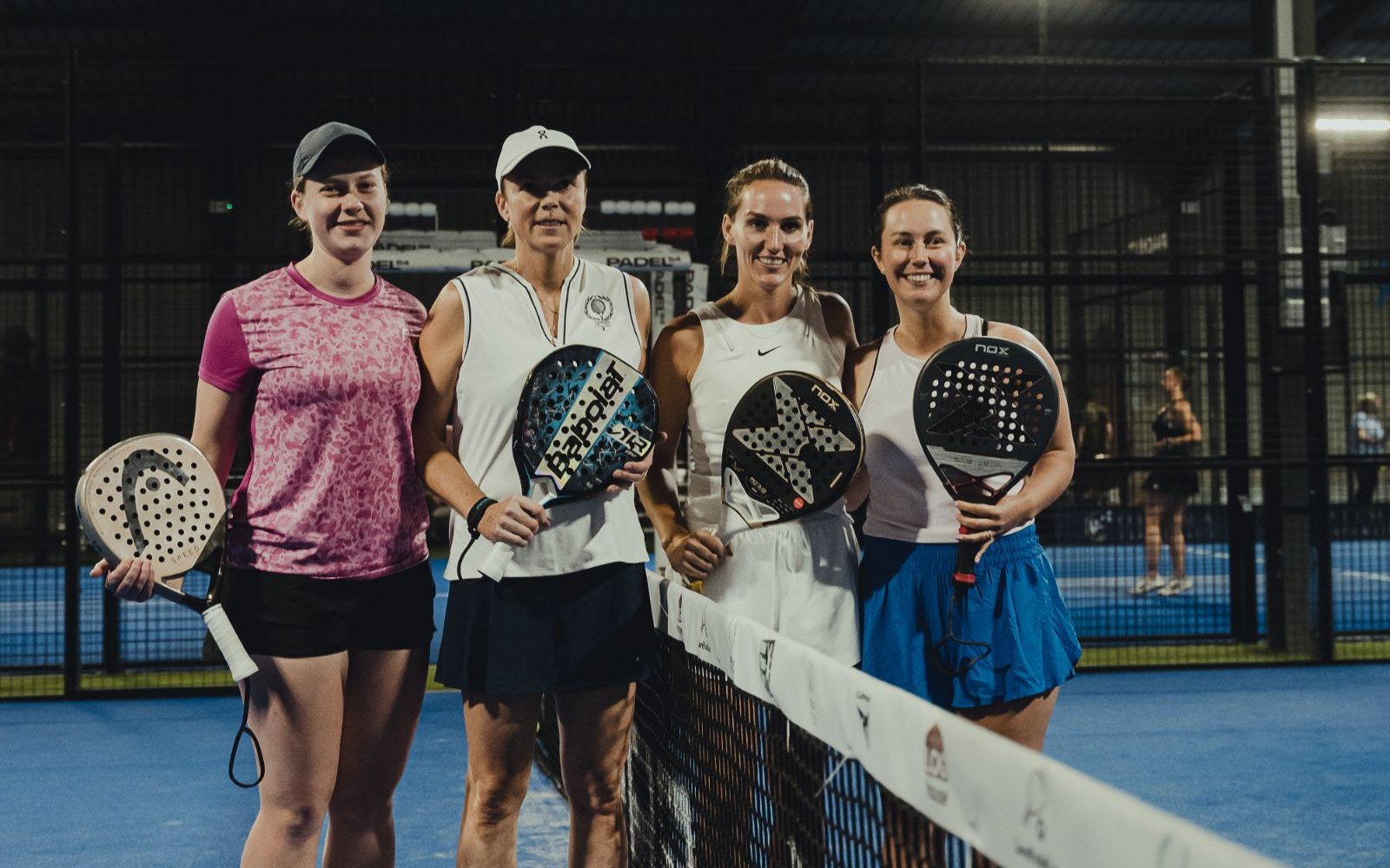 Four women players line up at the net before a match at Padel54
